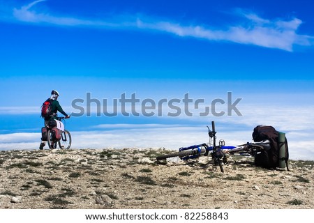 Young man riding a bike over the precipice in the mountains