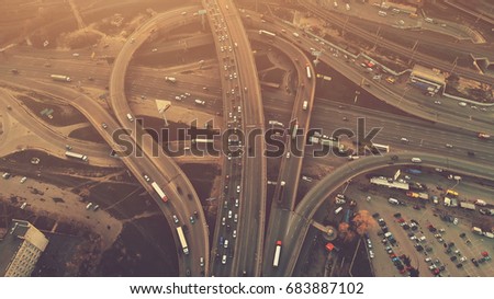 Aerial high drone flight over evening road traffic in Kiev, Ukraine. Highway and overpass with cars and trucks, interchange, two-level road junction in the big city. Top view. Vintage filter toning
