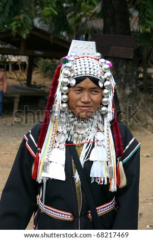 AKHA HILL TRIBE VILLAGE, CHIANG RAI, THAILAND - JAN 12:  Akha woman models traditional clothing and jewelery to passing tourists in her village in Thailand, January 12, 2010