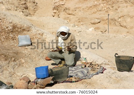 LUXOR, EGYPT- January 9:  Unidentified worker cleans off shards of pottery at an archaeological excavation at the Valley of the Kings on January 9, 2009 on the West Bank of the Nile, Luxor, Egypt.