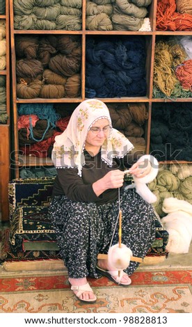 UCHISAR, TURKEY-AUGUST 7: A Turkish woman demonstrates the spinning of fine silk threads into yarn at a carpet factory on August 7, 2011 in Uchisar Turkey.