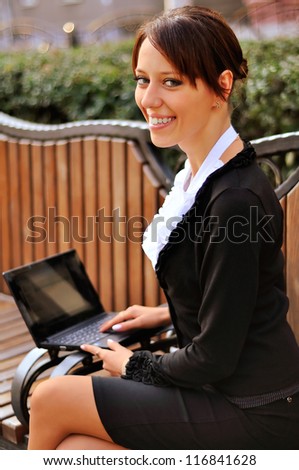 Businesswoman sitting on a bench with open smile turned to look at the camera