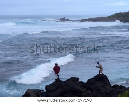 Two senior men surf fishing off the ocean rocks