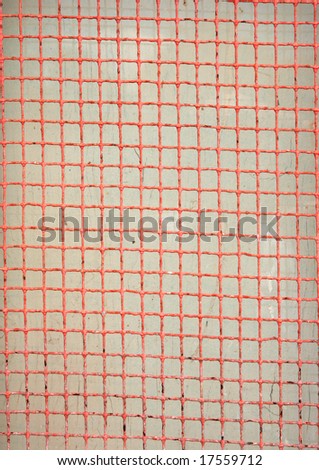 Old red metal mesh screen over off-white, useful as background