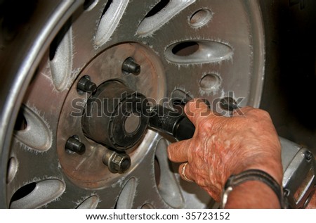 Mechanic using impact wrench to remove a flat tire.
