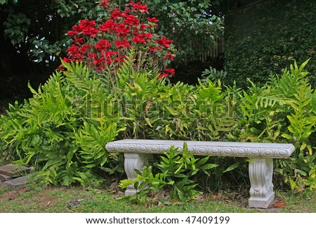 White concrete bench in a garden setting with red flowers