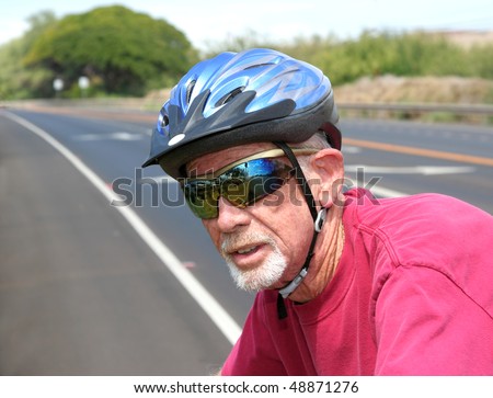 Athletic senior man riding a bicycle wearing a helmet