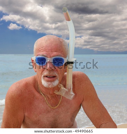 Senior man in snorkel and blue goggles at the ocean shore
