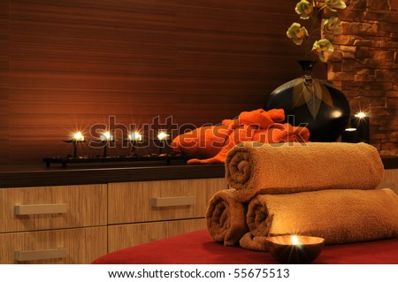 Wellness and spa concept with candles, collection of towels and part of massage table.