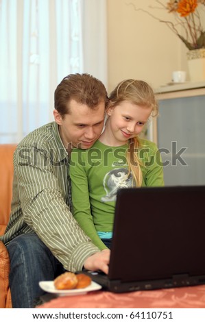 Father and his teenage daughter playing on a portable computer at home.