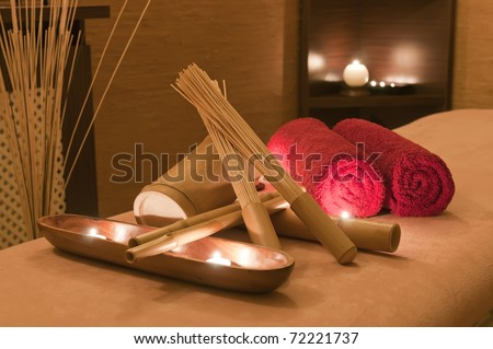 Wellness and spa concept with candles, red towels and part of massage table.