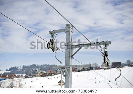 Ski lift gears against a blue sky and ski resort.
