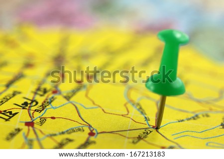 Pushpin pointing place on a paper map