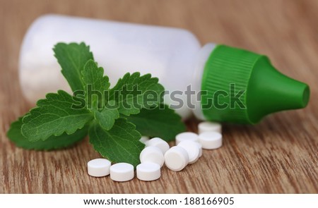 Stevia with sweetening tablets and bottle on wooden surface