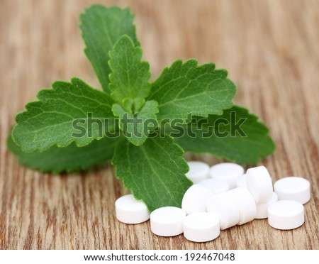 Stevia with tablets on wooden surface