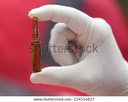 Close up of an ampoule holding by hand with gloves