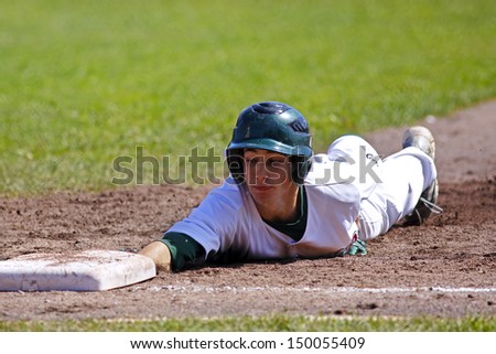 SHERBROOKE, CANADA - August 6: Shawn Bartley of New Brunswick slides back to first base in men\'s baseball at the Canada Games August 6, 2013 in Sherbrooke, Canada.