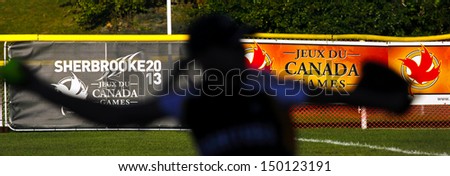 SHERBROOKE, CANADA - August 5: A women\'s softball pitcher is silhouetted against Canada Games signage August 5, 2013 in Sherbrooke, Canada.