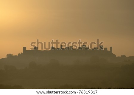 The silhouette of the Castle of Monteriggioni in a golden sunrise (Italy)