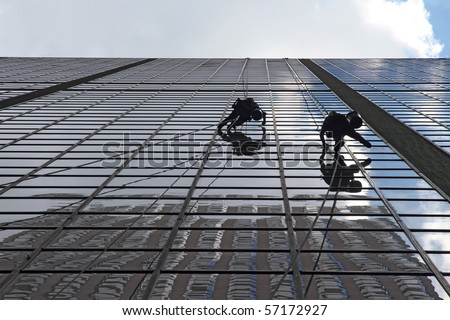 Maintenance workers climbing outside a skyscraper and clean windows