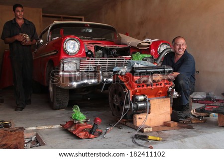 TRINIDAD, CUBA, FEBRUARY 18, 2014 : Men to repair classic old American car in garage. Classic cars are still in use in Cuba and old timers have become an iconic view and a worldwide known attraction.