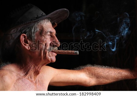 VINALES, CUBA, FEBRUARY 22, 2014 : A farmer smoking cigar in a tobacco drying shed near Vinales. Cuba has the second largest area planted with tobacco of all countries world wide.