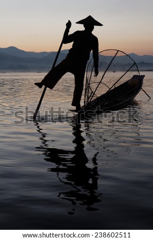 INLE LAKE, BURMA, December 14, 2014 : Fishermen on Inle lake in morning light. These fishermen are practicing a distinctive rowing style, wrapping a leg around the oar.