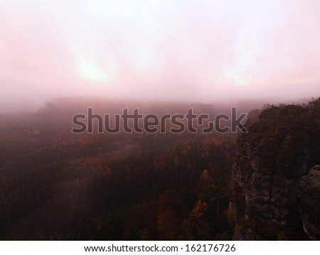 Pink daybreak in a beautiful mountain of Saxony Switzerland. Sandstone peaks and hills increased from pinkfoggy background, the fog is pink-orange due to first sun rays.