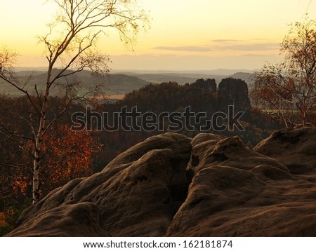 Autumn evening view over sandstone rocks to fall valley of Saxony Switzerland. Sandstone peaks and hills increased from colorful background.