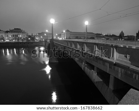 Night bridge over river to historical part of town, reflections in water level.