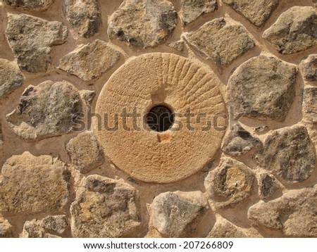 Water mill stone in stony wall from nature material, broken marl stone , traditional building materials.