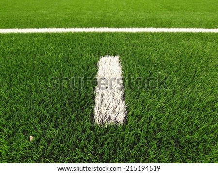 White line marks painted on artificial green turf background. Winter football playground with plastic grass.