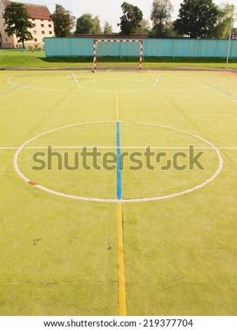 Empty outdoor handball playground, plastic light green surface on ground and white blue bounds lines.