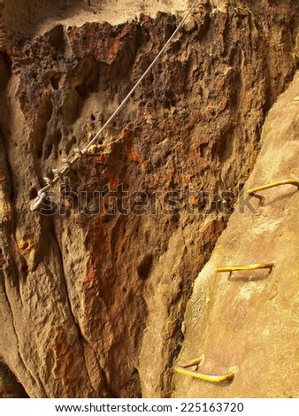 Climbers way. Iron twisted rope fixed in block by screws snap hooks. The rope end anchored into sandstone rock.
