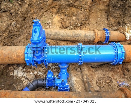 New blue valves and new blue joint members on old big drink water pipes joined. Finished repaired piping waiting for covering by clay. Extreme kind of corrosion, metal corroded texture.