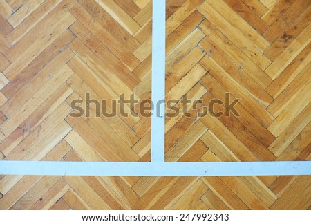 Worn out wooden floor of sports hall with colorful marking lines.