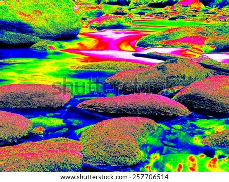 Mossy stones in mountain river in infrared photo. Amazing thermography. Boulders and water level in shadows of trees.