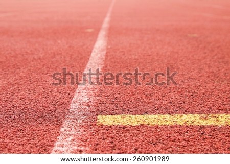 White and yellow lines and arrow. Textured red rubber of running racetracks in outdoor stadium