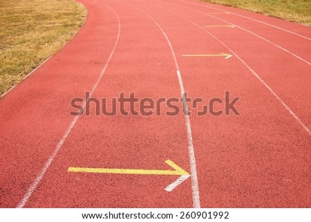White and yellow lines and arrow. Textured red rubber of running racetracks in outdoor stadium
