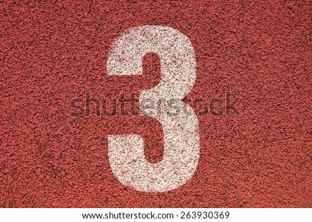 White track number on red rubber racetrack, texture of running racetracks in small stadium