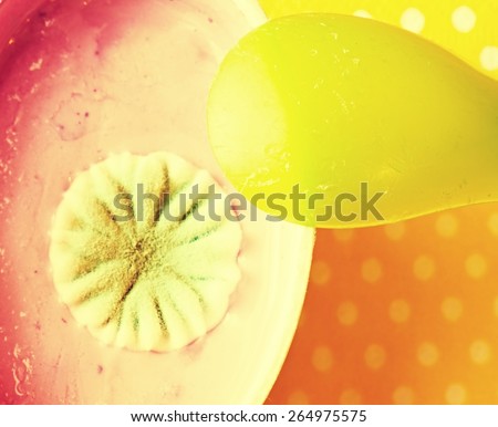 Plastic cup of pink fruit yogurt with ugly circle blossom of poisonous mold. Yellow green plastic spoon.