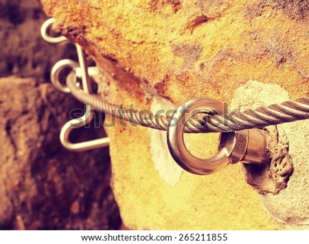 Climbers rope path. Iron twisted rope fixed in block by screws snap hooks. The rope end anchored into sandstone rock.