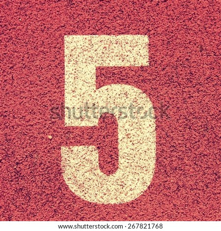 Number five. White track number on red rubber racetrack, texture of running racetracks in small stadium