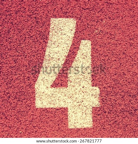 Number four. White track number on red rubber racetrack, texture of running racetracks in small stadium