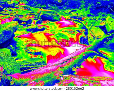 Foamy water level of waterfall, curves between boulders of rapids. Cold water of mountain river in infrared photo. Amazing thermography.