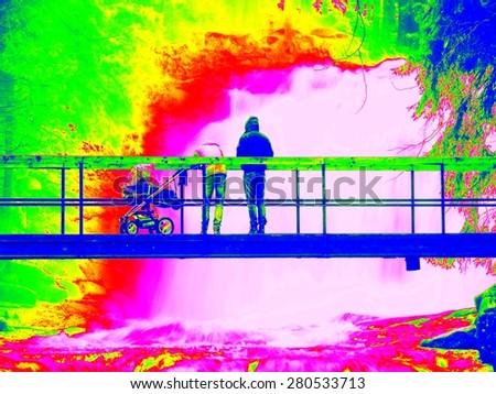 Foamy water level of waterfall, bellow footpath bridge with people. Cold water of mountain river in infrared photo. Amazing thermography.