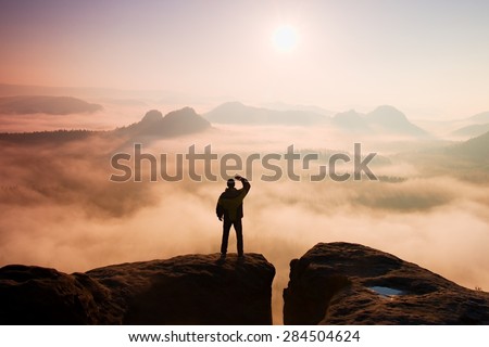 Man stands on the peak of sandstone rock in national park Saxony Switzerland and watching to Sun. Beautiful moment the miracle of nature