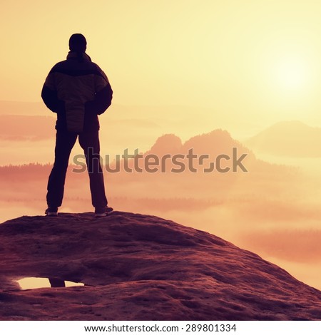 Hiker standing on top of a mountain and enjoying sunrise