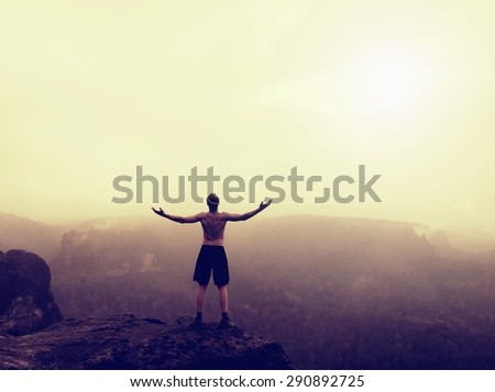 Gesture of triumph.. Climber in black pants.  Naked tourist on the peak of sandstone rock in national park Saxony Switzerland watching into misty landscape.