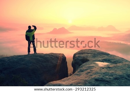 Moment of loneliness. Man on the rock empires  and watch over the misty and foggy morning valley.